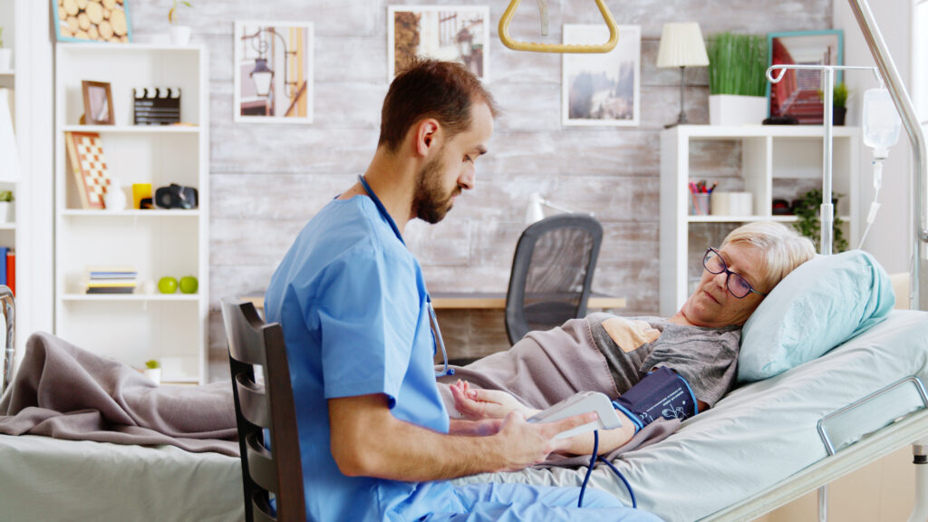 in retirement home male nurse checks old sick lady blood pressure